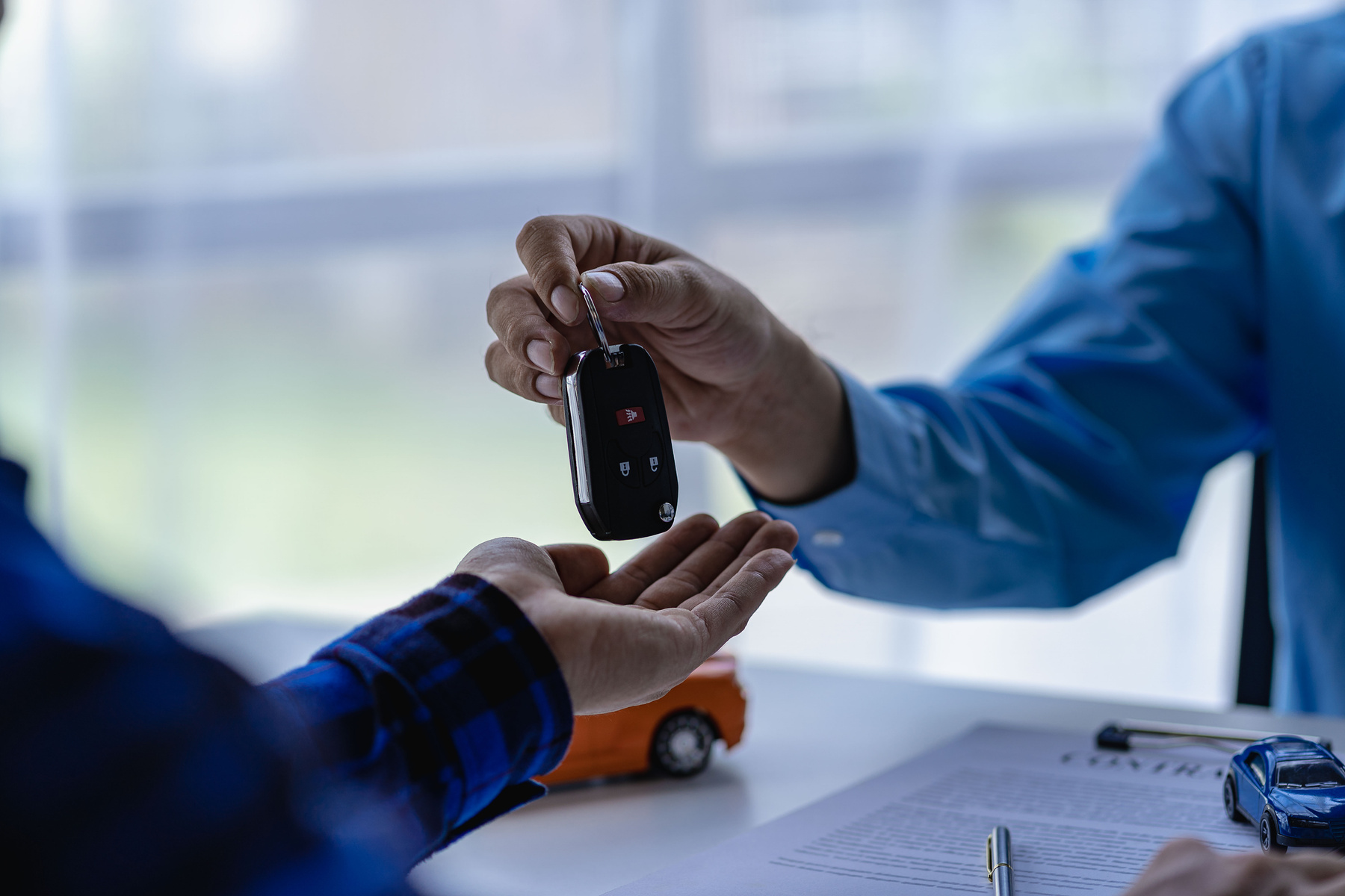 Young salesman holding car keys in hands of car rental business customer sell or buy services Asian male sales representative sells important cars to client tenants.